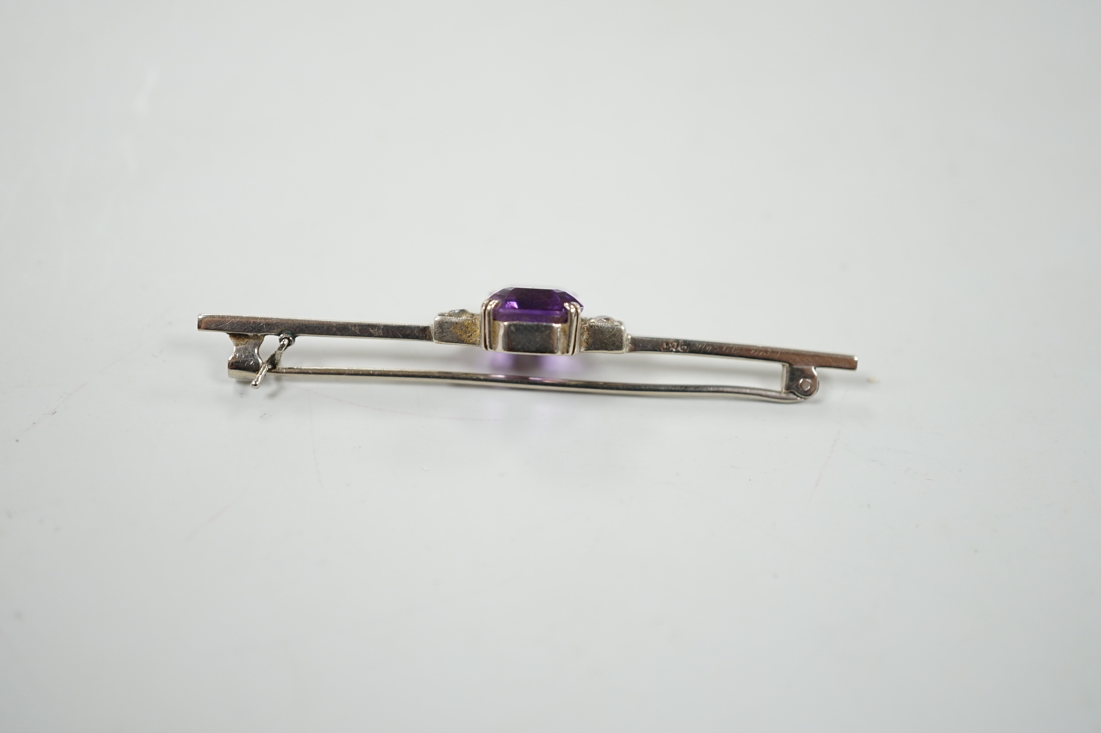 A 9ct white metal, amethyst and diamond set three stone bar brooch, 56mm, gross weight 3.7 grams, with original 1950's receipt.